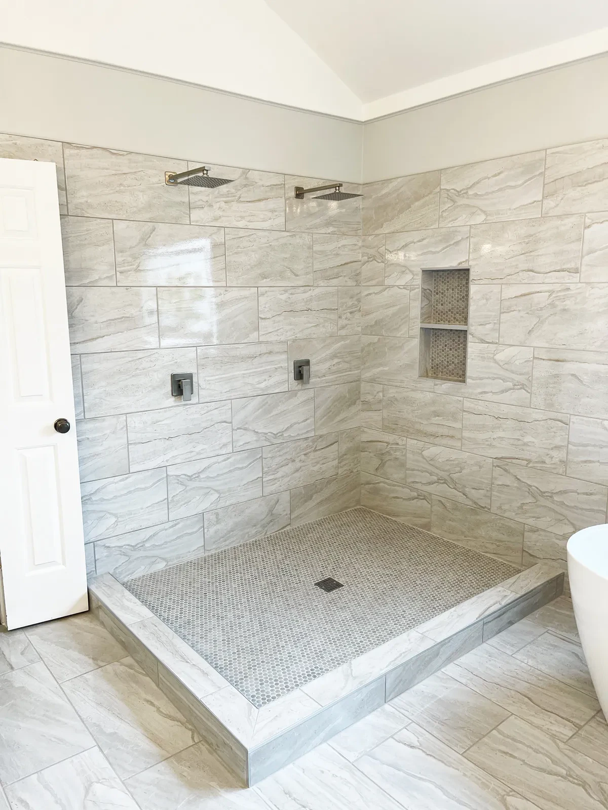 Modern bathroom with tiled walk-in shower and white door