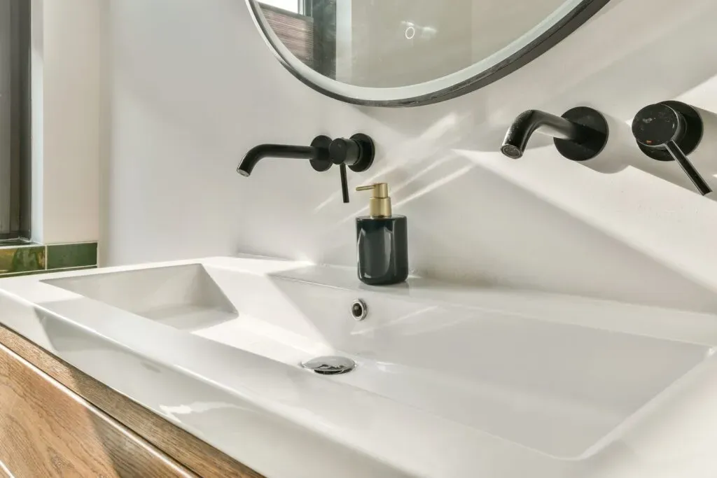 Modern bathroom sink with black faucets and mirror