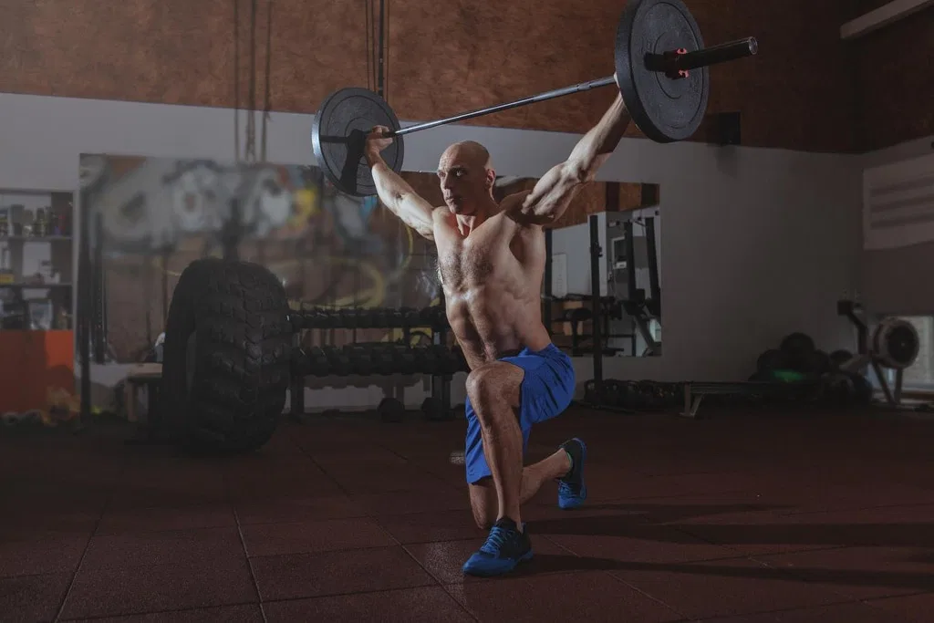 strong male crossfit athlete exercising with heavy barbell